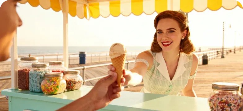 Seaside candy stall handing a cone over jars of colourful sprinkles